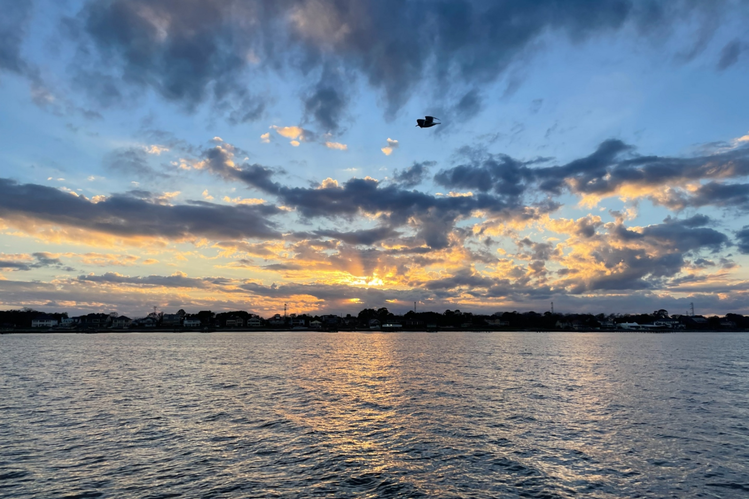 Sunset over Galveston Bay with dramatic clouds reflected on the water.
